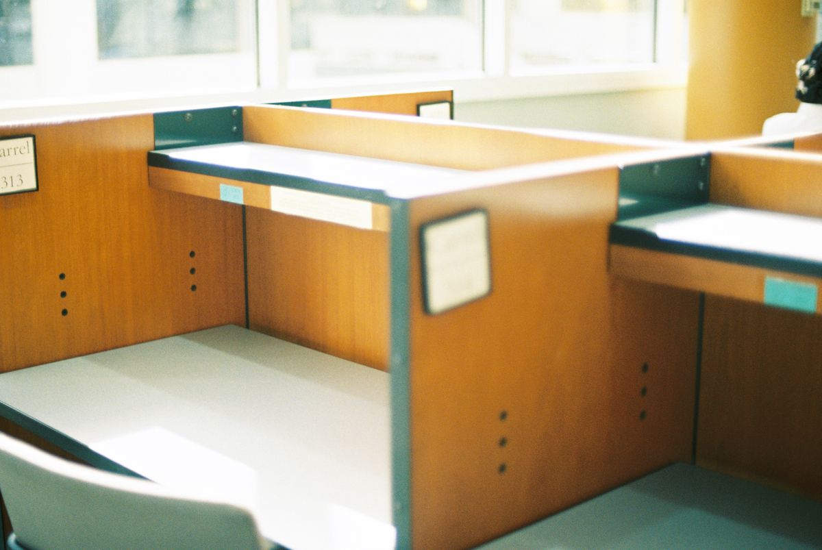 An emptied office cubicle, its desk bare, beside a window.